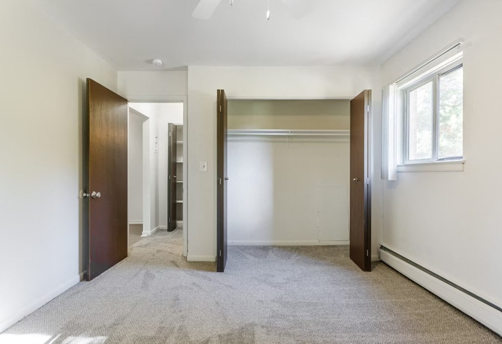 a bedroom with white walls and a closet and a window